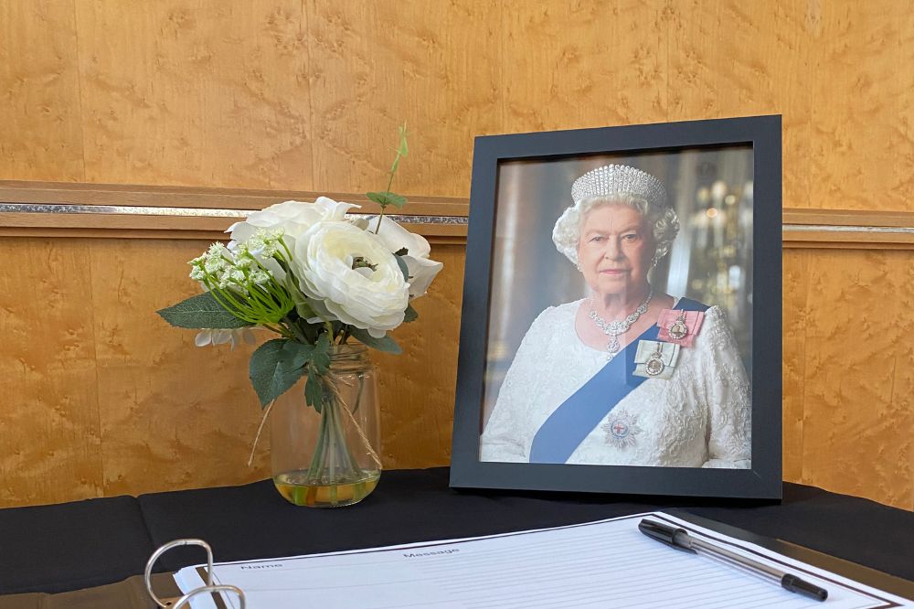 Condolences book on a black table with a portrait of the Queen and a jar of flowers