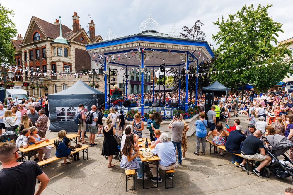 Crowds sit at tables around the Carfax bandstand enjoying the sun and the event