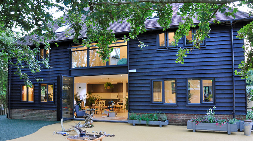 A contemporary barn conversion project. The wood-clad property has large windows to flood the modern interior with light