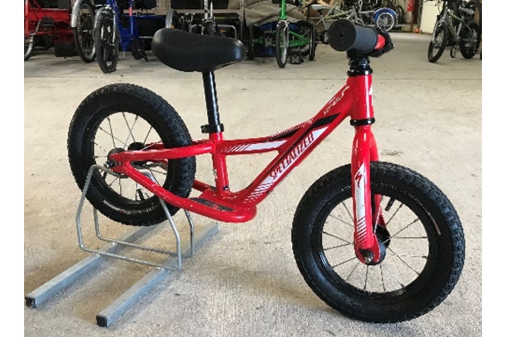 A red two-wheeled balance bike with no pedals