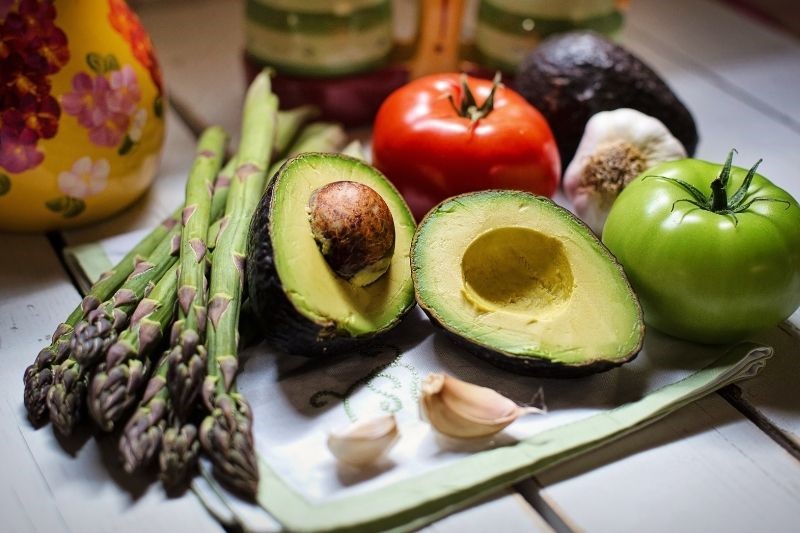 Asparagus, avocado, tomatoes and garlic on a chopping board