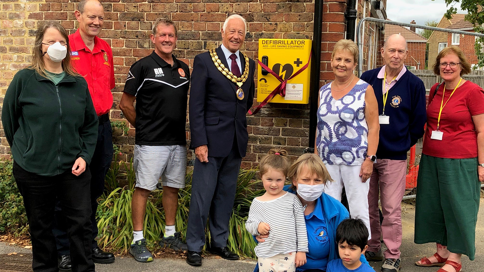 HDC Chairman Cllr David Skipp and Pat Pigott with community members unveil the new defibrillator