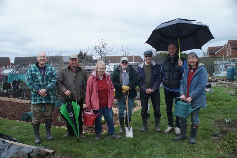 Lower Barn Allotment society members gather in the gardens with tools and umbrellas