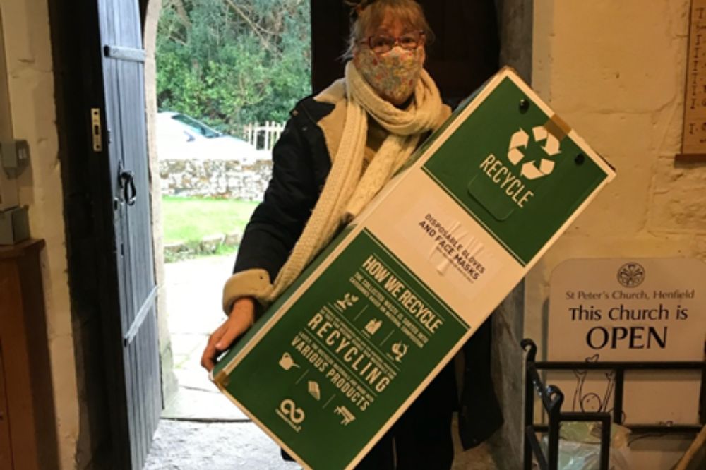 A volunteer holding up a TerraCycle collection box at St Peter's Church, Henfield
