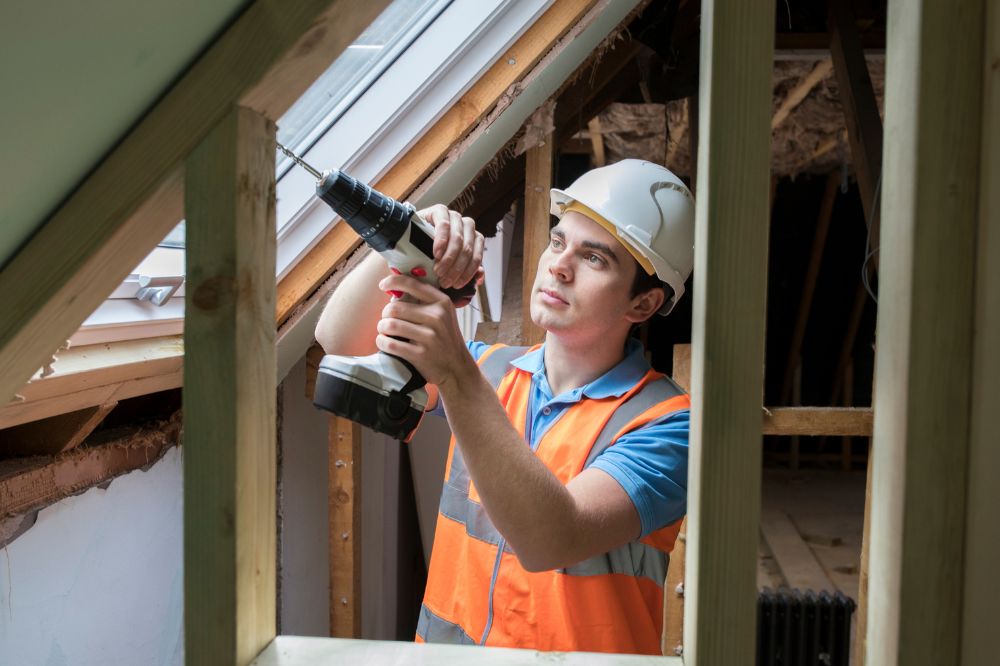 A man in a hard hat working in a loft