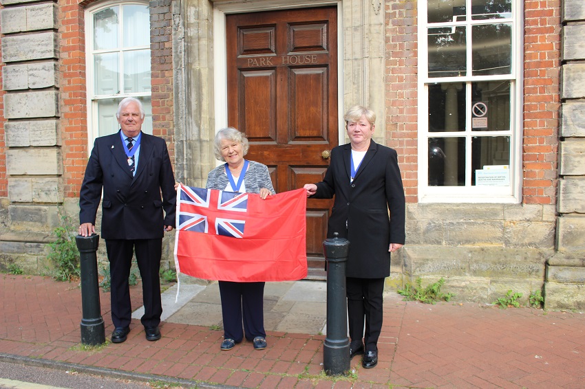 Cllr Peter Burgess Armed Forces Champion Vice Chairman Kate Rowbottom and Cllr Karen Burgess with the Red Ensign flag