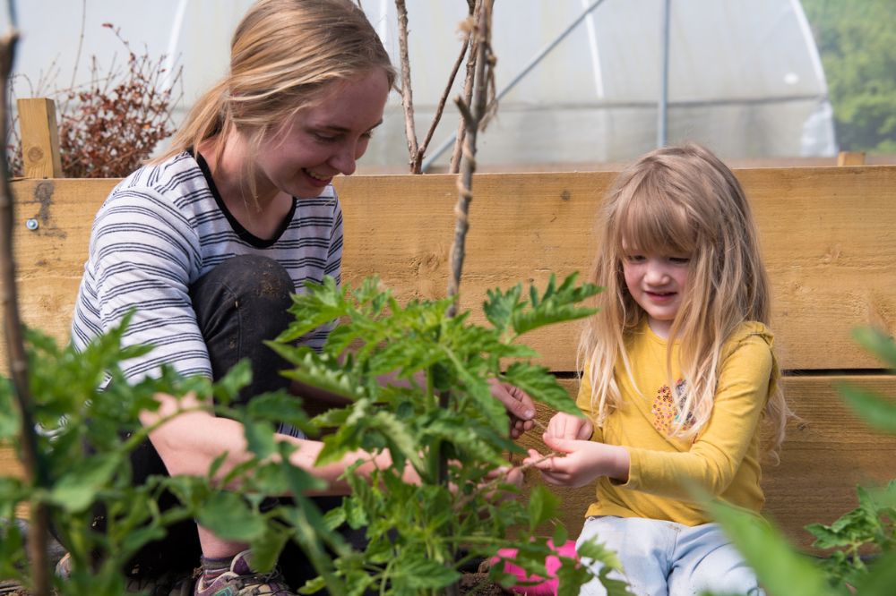 A young child and an adult woman are gardening in Rock Farm's community garden