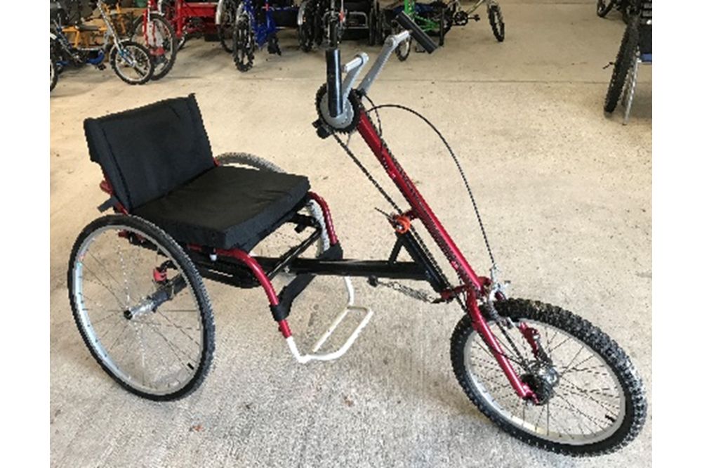 A red hand-powered trike with full seat