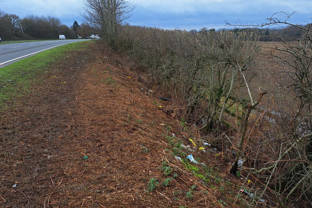 A view of the highway with lots of litter in the verge that has been thrown from cars
