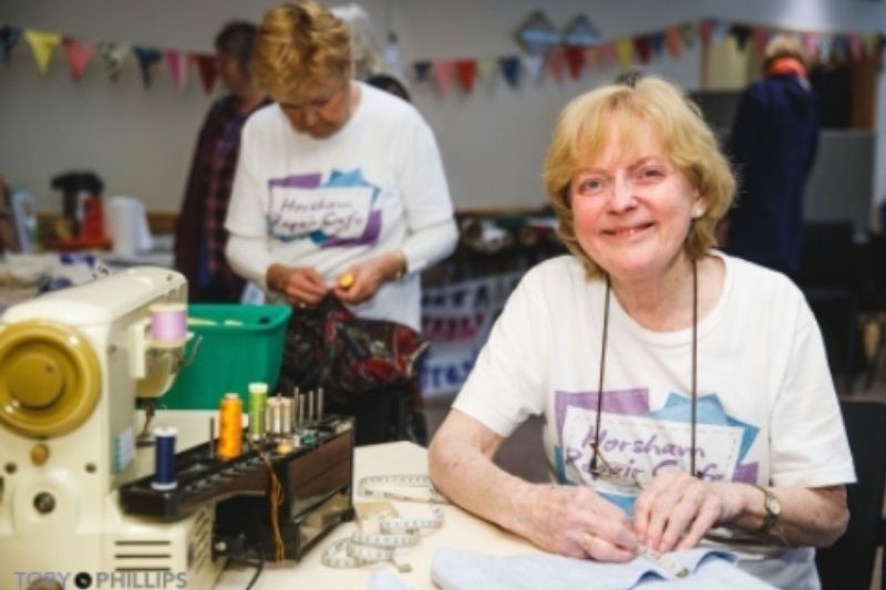 A member of Horsham Repair Cafe sits with a sewing machine