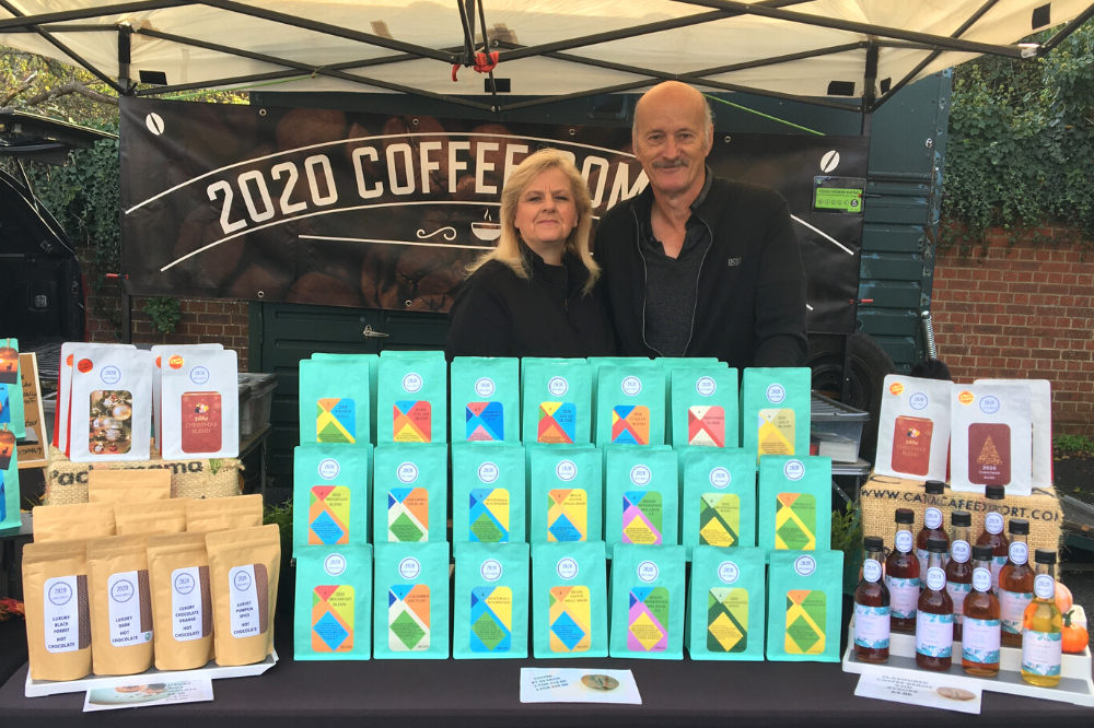 Two people at a market stall selling coffee