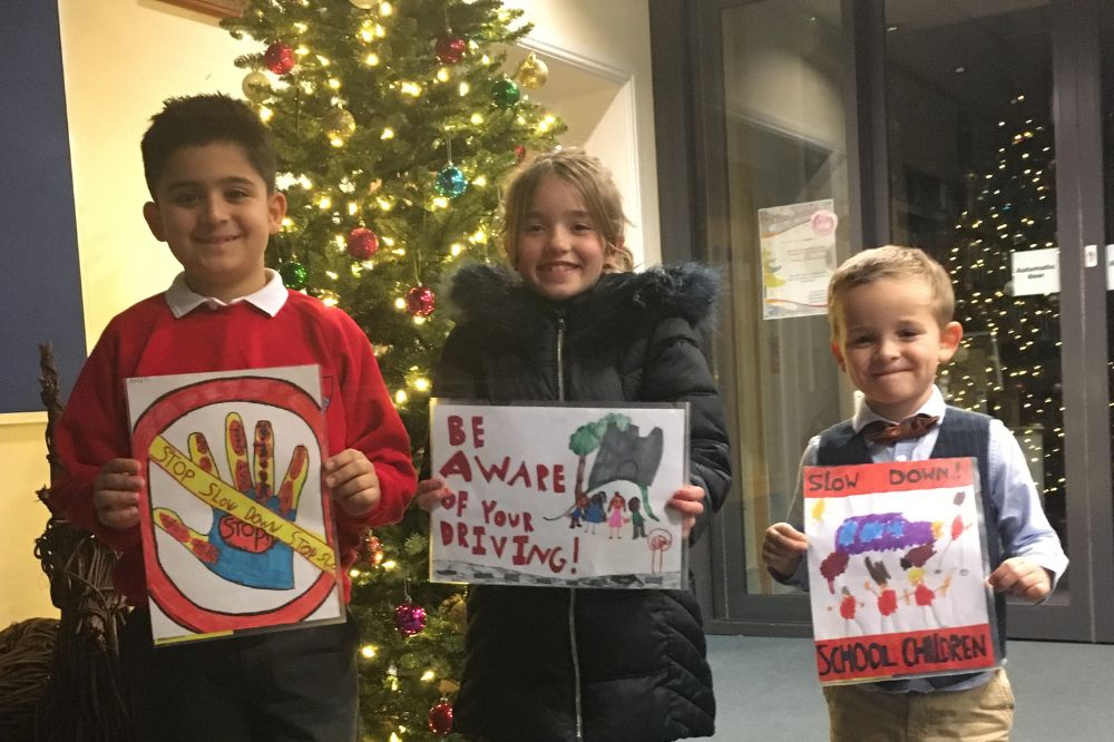 Three children proudly holding their designs